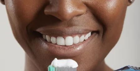 A lady holding a toothbrush with toothpaste on it