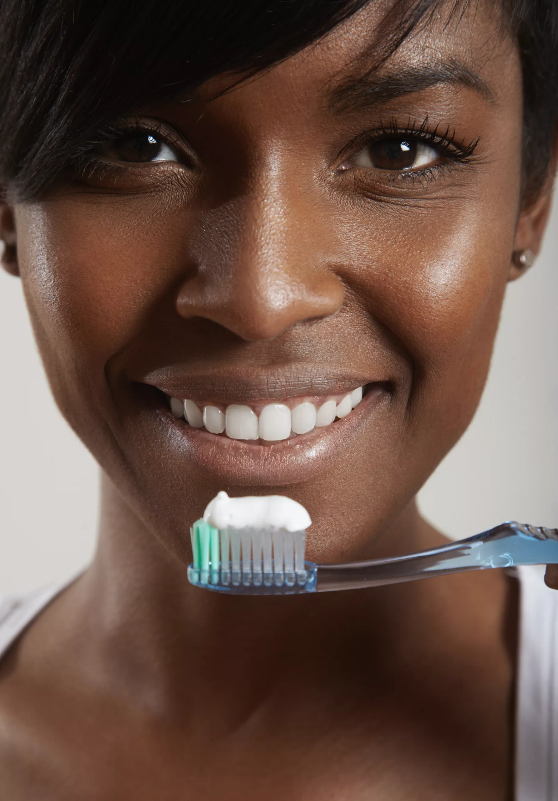 A lady holding a toothbrush with toothpaste on it